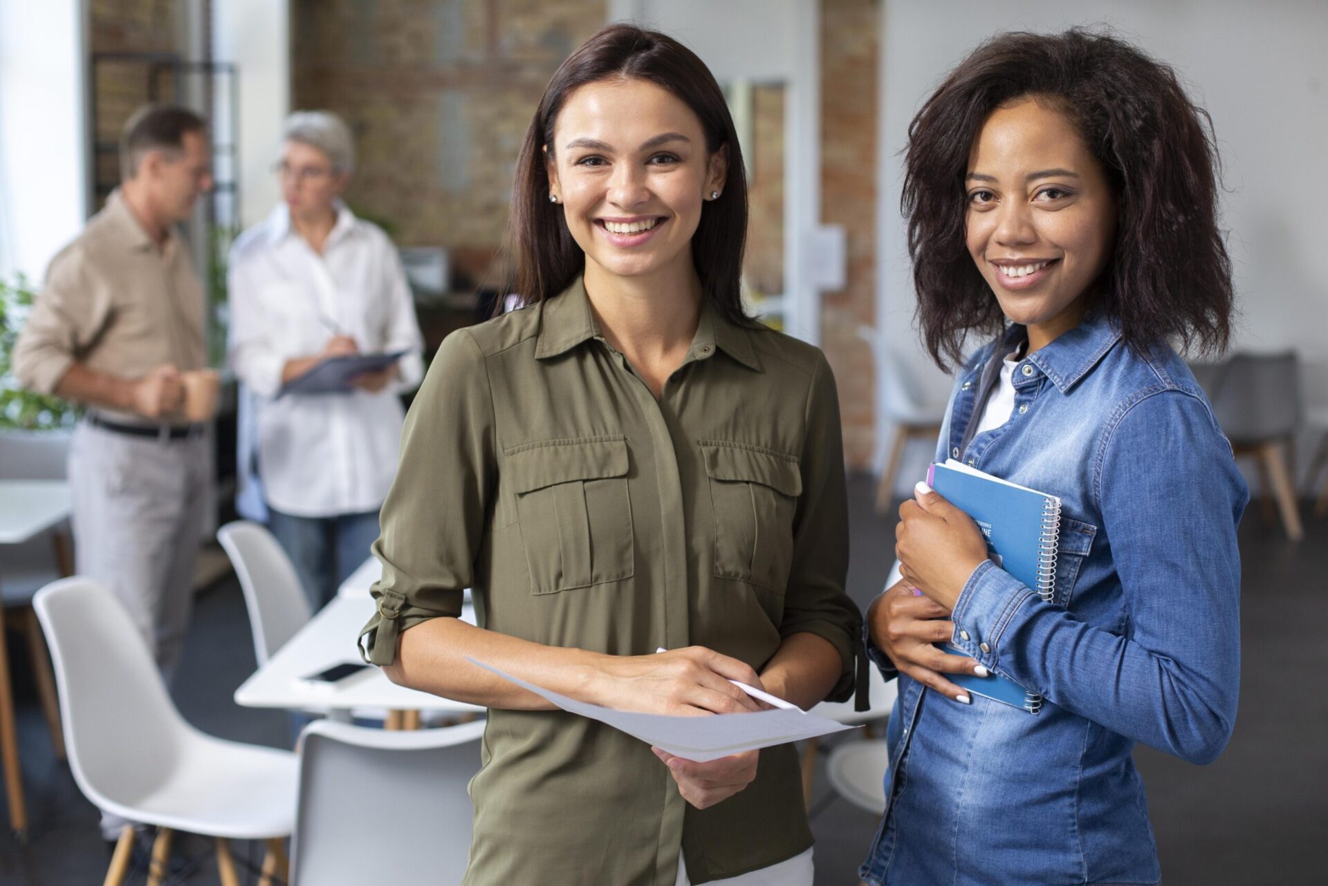 Mulheres estão sorrindo em foto durante reunião de trabalho