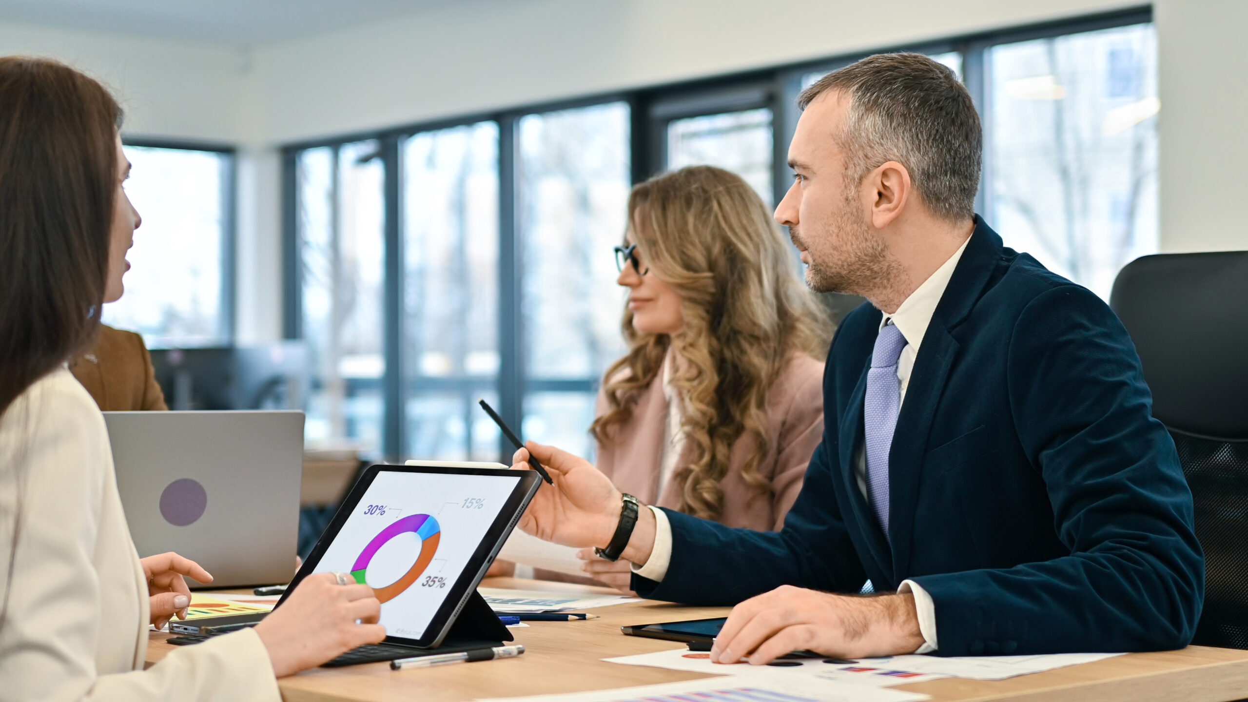 Reunião de negócios em um escritório, trabalhadores discutindo assuntos de negócios. Gadgets e papéis com gráficos em cima da mesa