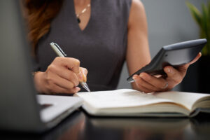 Foto de uma mulher de negócios fazendo cálculos e tomando notas